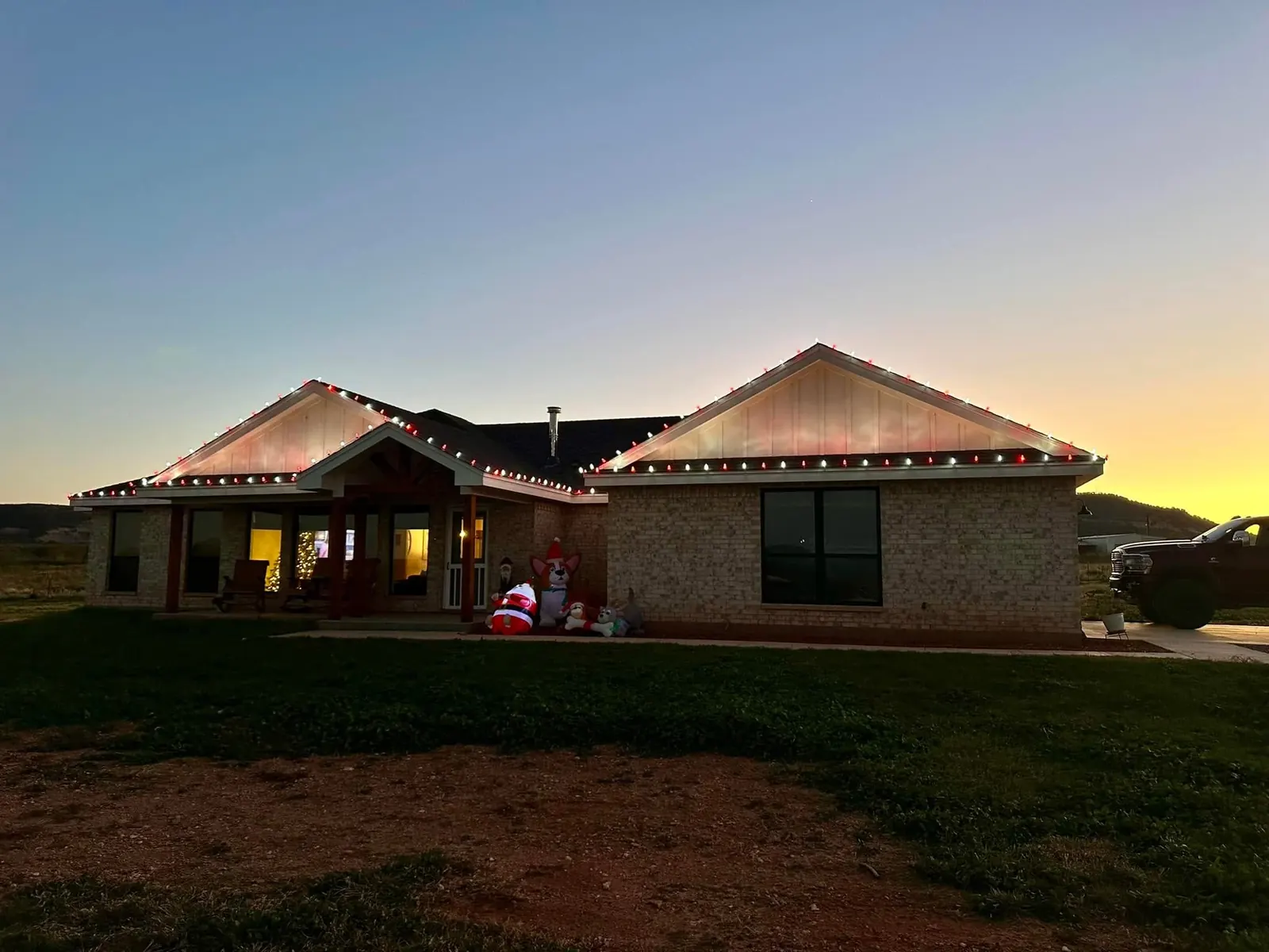 A house with red and white roofline lights and outdoor Christmas decorations