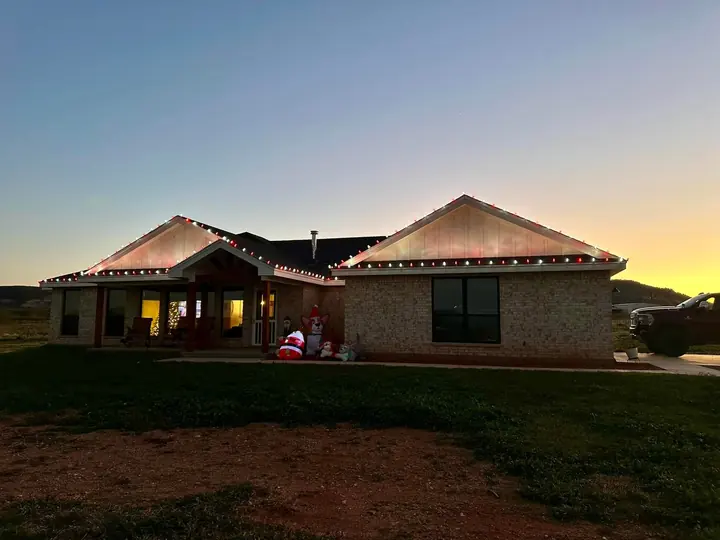 A house with red and white roofline lights and outdoor Christmas decorations