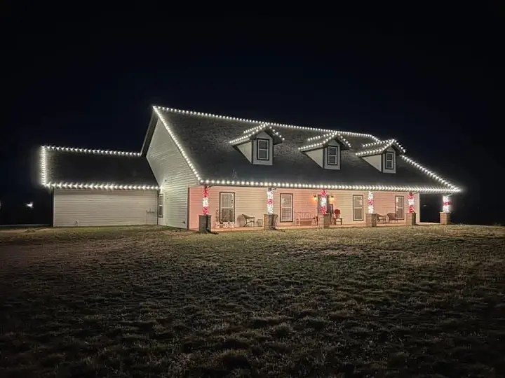 Warm white lights tracing roof peaks, dormers and ridges on a farmhouse