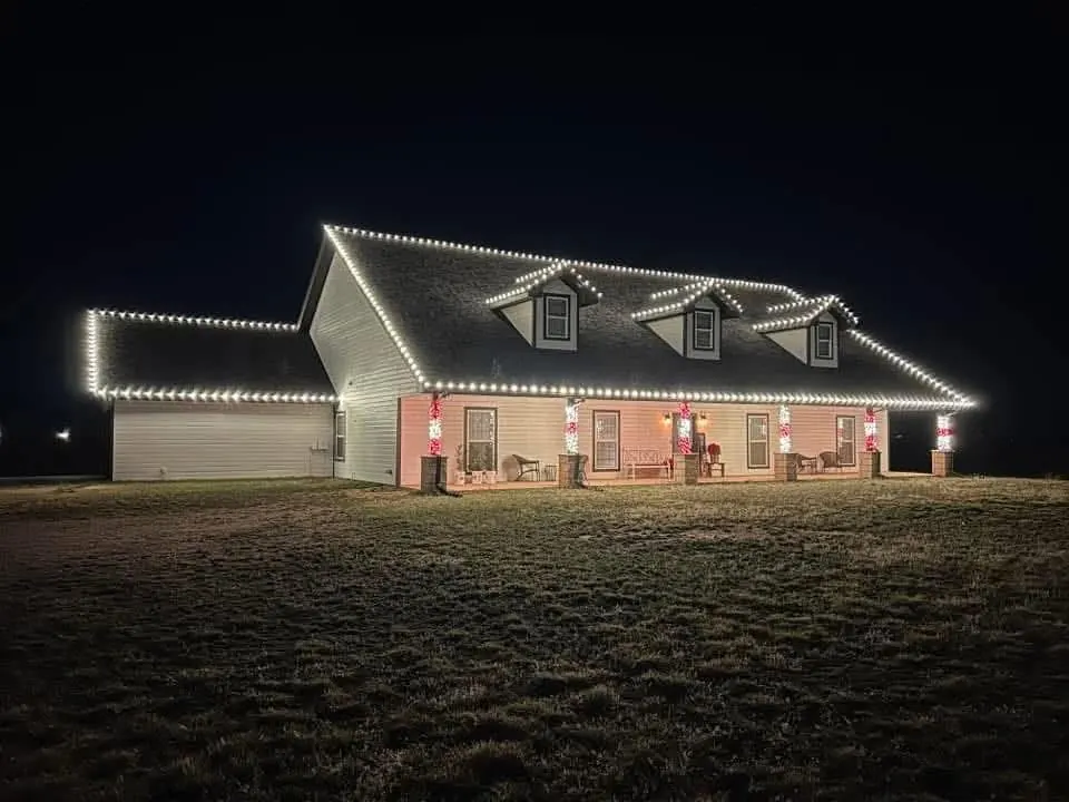 A farmhouse glowing with warm white Christmas lights